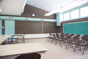 Classroom with long tables and rows of folding chairs