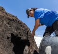 Woman in a blue shirt and hat holding a shovel and scooping dirt