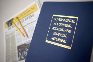 A Government Accounting, Auditing, Financial Reporting book on top of a Wall Street Journal Newspaper 