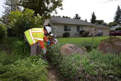Worker creating a space for a sewer lateral on the side of a house.